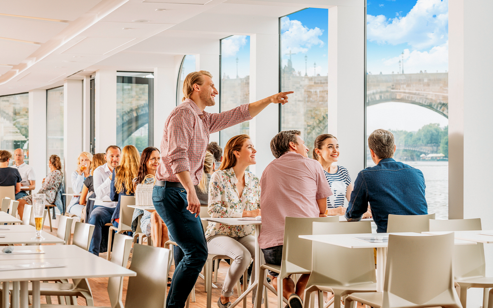 Guests dining with view of Vltava River on sightseeing cruise in Prague.