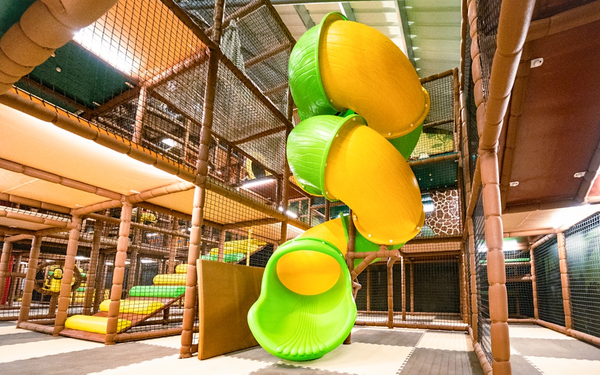 Indoor safari playland with spiral slide and climbing structures.