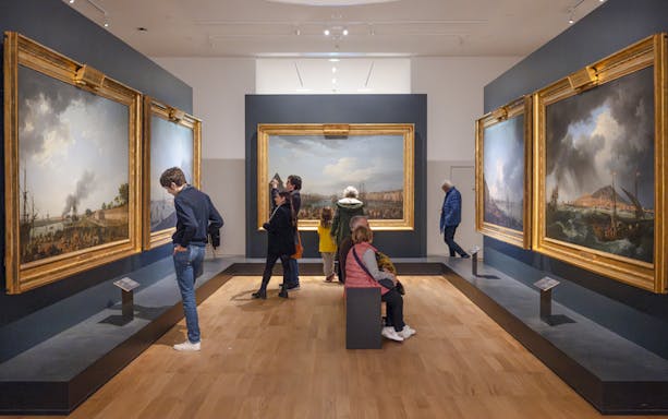 Visitors viewing maritime paintings at National Marine Museum, Paris, France.