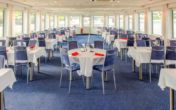 Dining area with set tables and blue chairs on MS Vienna cruise ship.