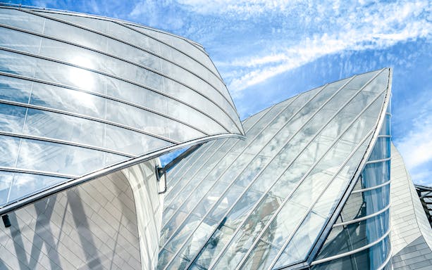 Fondation Louis Vuitton's glass architecture under a blue sky in Paris.
