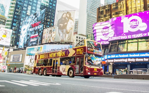 Big Bus tour passing through Times Square, New York City, with bright billboards.