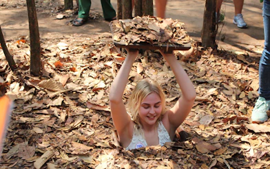 Visitor emerging from a hidden entrance at Cu Chi Tunnels during VIP speed boat tour.
