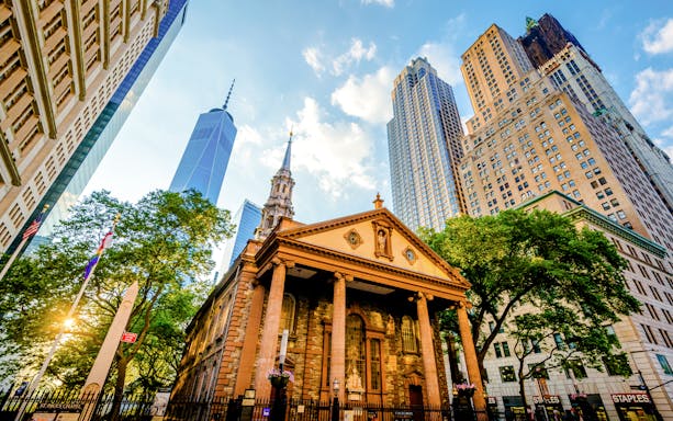 Saint Paul's Chapel at sunset with skyscrapers in Lower Manhattan.