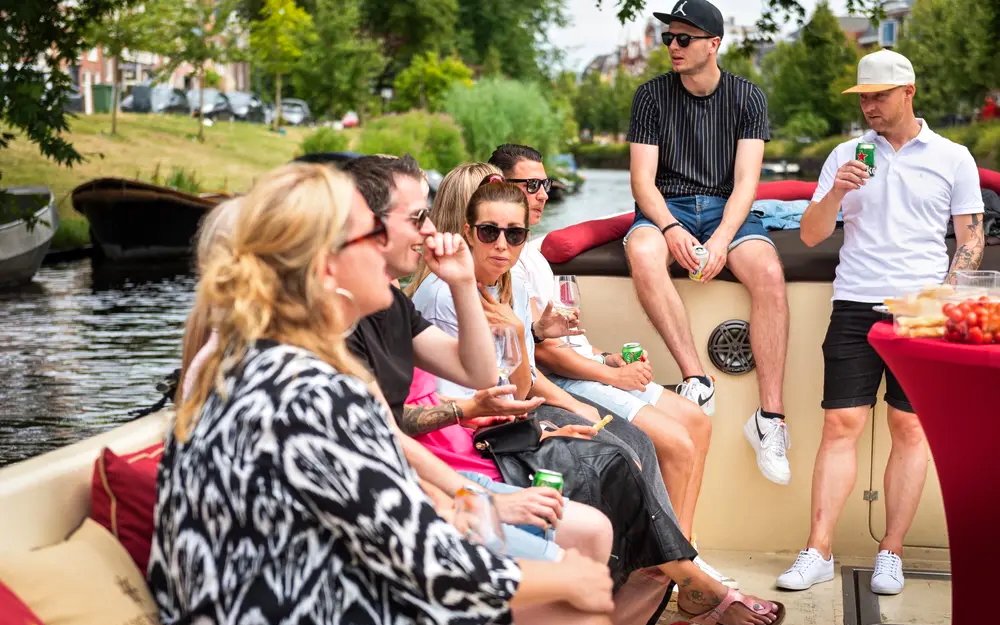 Group enjoying Harlem canal cruise on open boat with drinks.