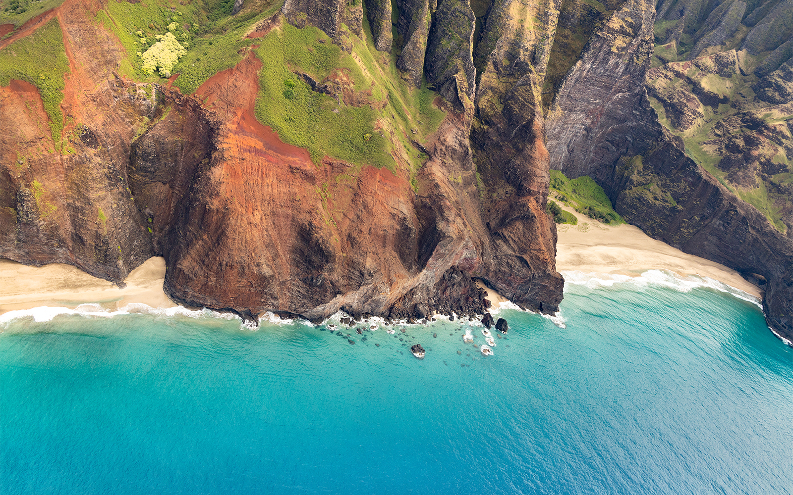 Aerial view of rugged cliffs and turquoise waters on a helicopter tour in Maui, Hawaii.
