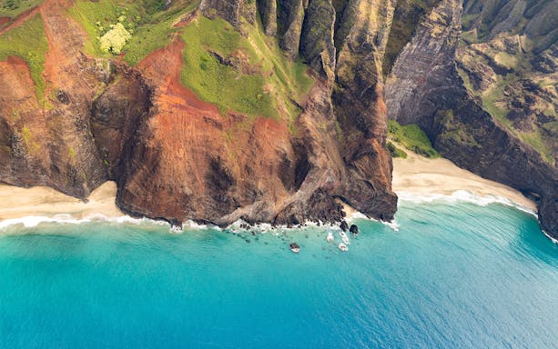 Aerial view of rugged cliffs and turquoise waters on a helicopter tour in Maui, Hawaii.