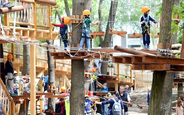 Children navigating a treetop adventure course at Paradis Land.