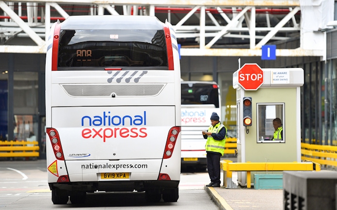 National Express bus at a stop with staff nearby.