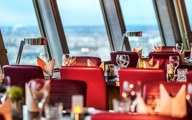 Dining tables set at Berlin TV Tower restaurant with panoramic city views.
