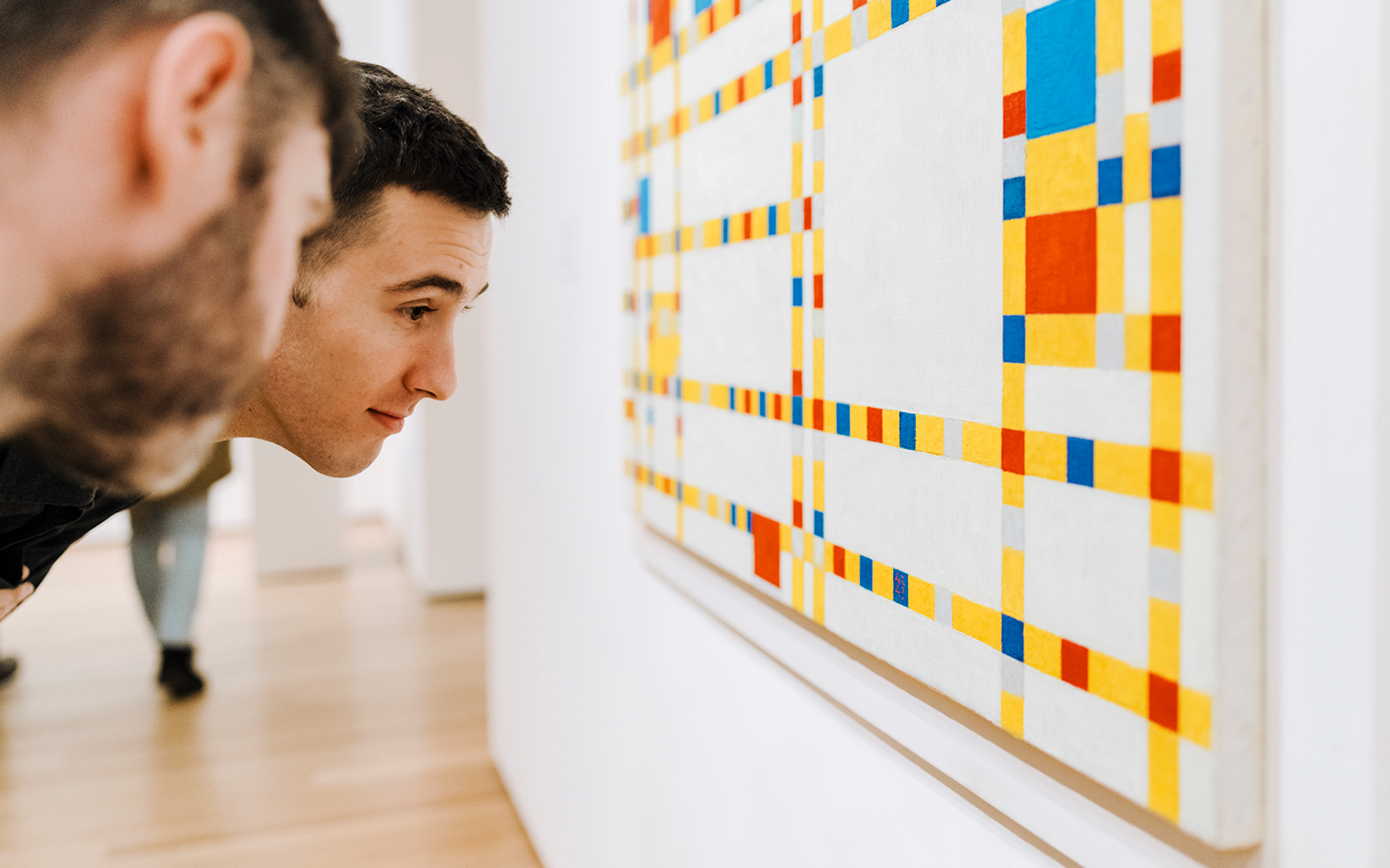 Visitors looking closely at the Mondrian artwork at MoMa