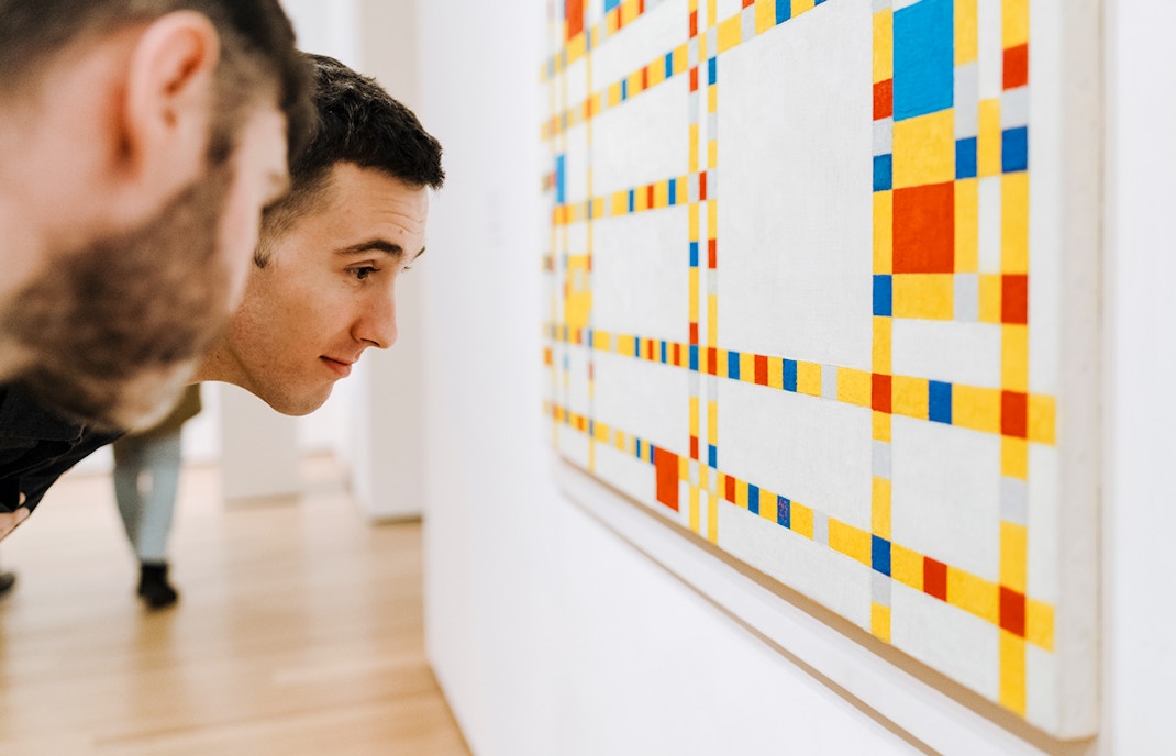 Visitors looking closely at the Mondrian artwork at MoMa