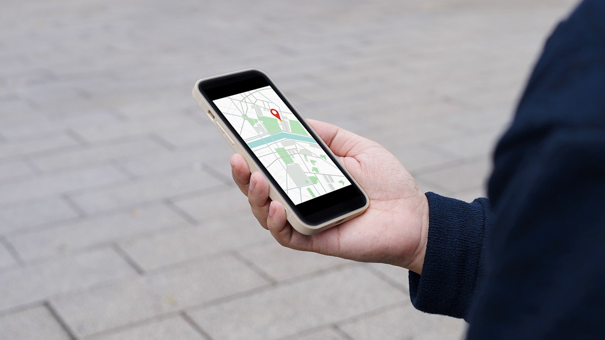 Traveler navigating city streets using a mobile map app in an urban setting.