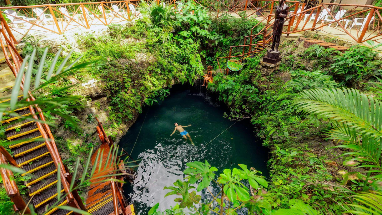 Swimming in a lush cenote surrounded by greenery, Cancun Extreme Adventure.