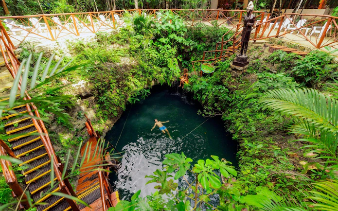 Swimming in a lush cenote surrounded by greenery, Cancun Extreme Adventure.