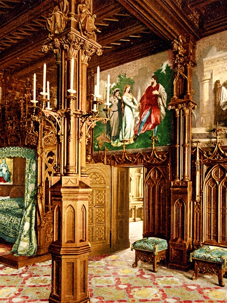Neuschwanstein Castle interior with ornate wooden carvings and colorful murals.