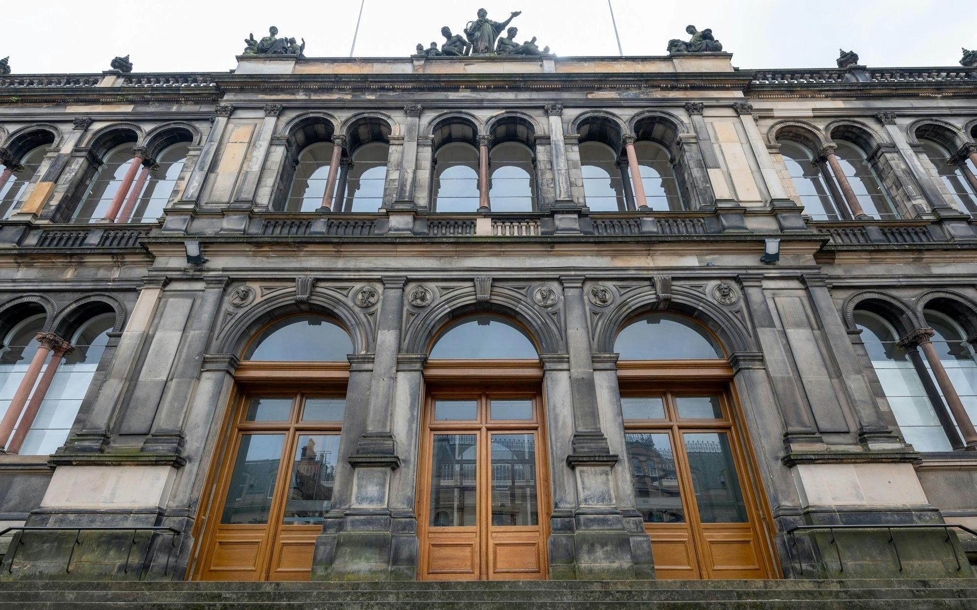 Facade of the National Museum of Scotland with arched windows and stone carvings.