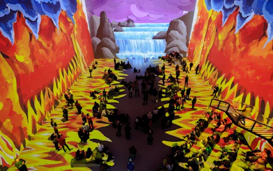 Visitors at David Hockney: Bigger & Closer exhibit, vibrant projections of nature scenes.