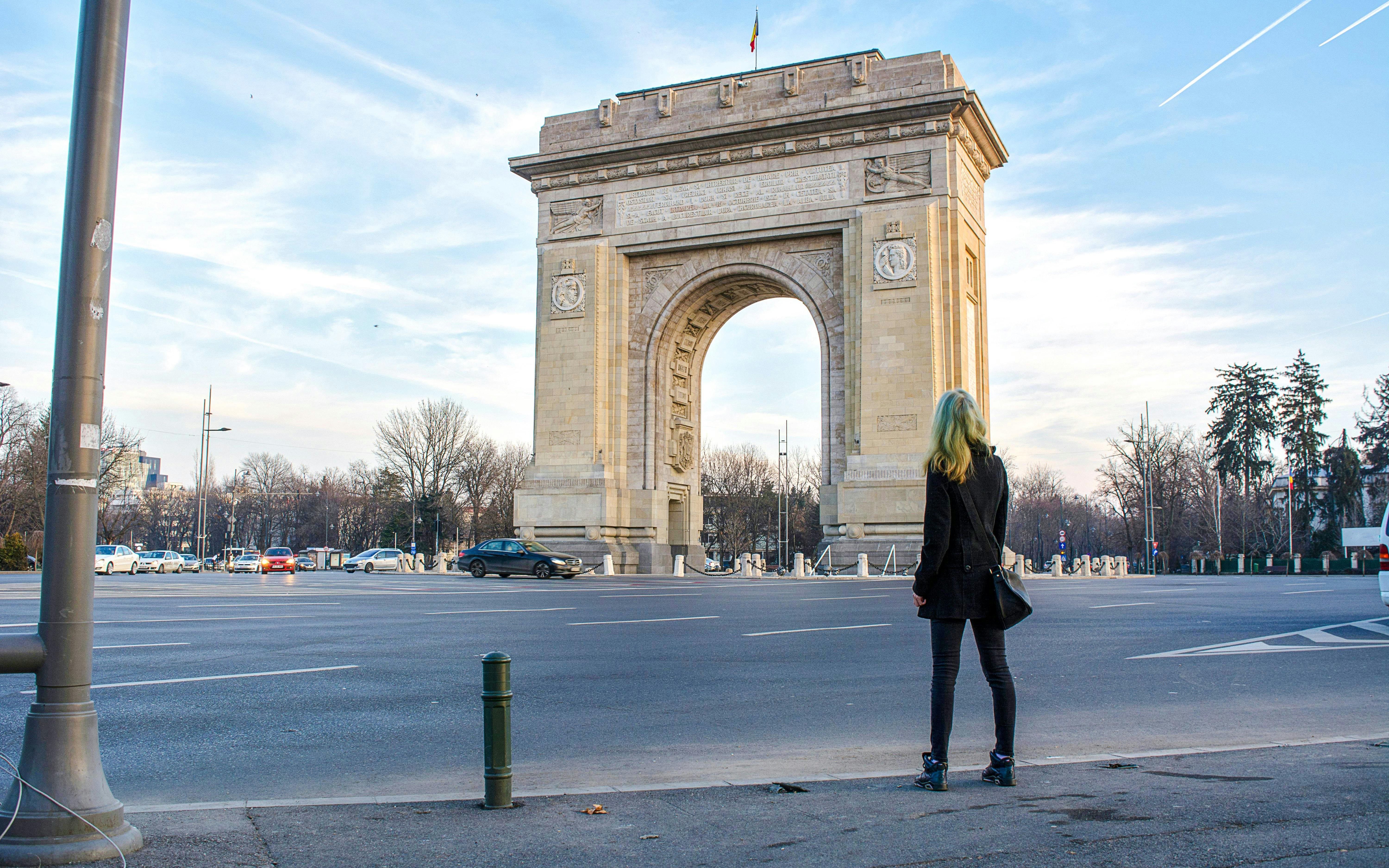 Arc de Triomphe in Bucharest with a person standing nearby.