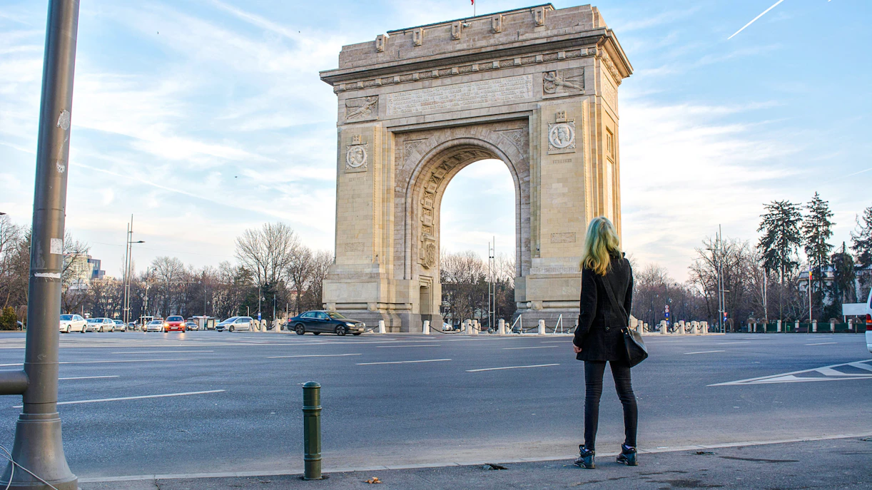 Arc de Triomphe in Bucharest with a person standing nearby.