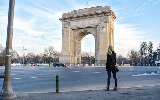Arc de Triomphe in Bucharest with a person standing nearby.