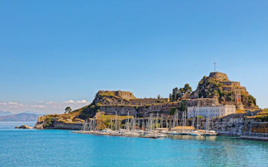 Old Port in Corfu town, Greece with sailboats and historic fortress.