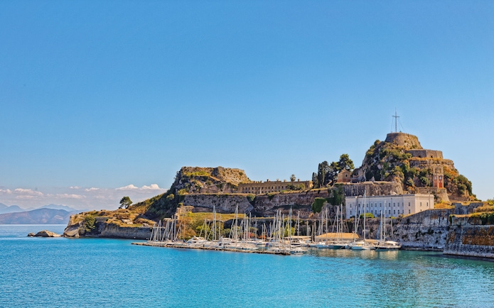 Old Port in Corfu town, Greece with sailboats and historic fortress.