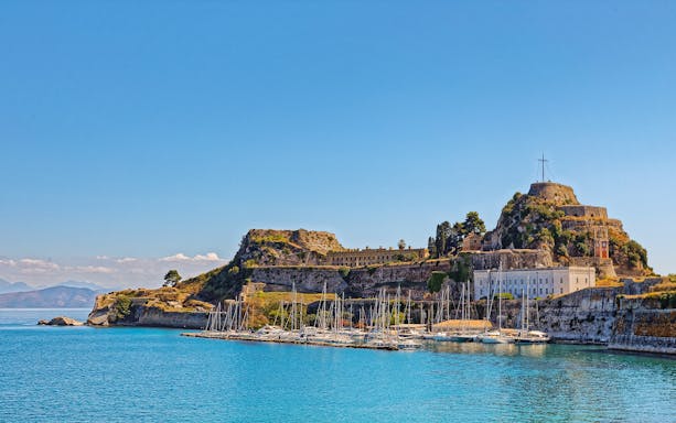 Old Port in Corfu town, Greece with sailboats and historic fortress.