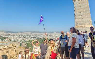 Tour group exploring the Acropolis in Athens with a guide holding a flag.