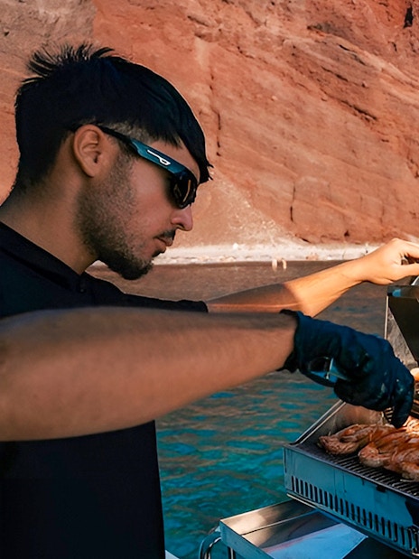 Grilling seafood on a boat near Santorini's red cliffs.