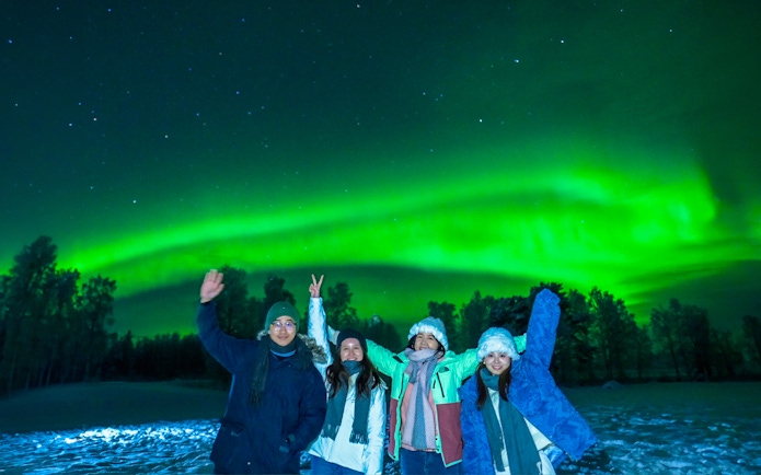 Guests in overalls viewing Northern Lights in Rovaniemi, Finland.