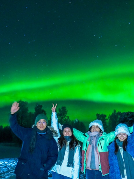 Guests in overalls viewing Northern Lights in Rovaniemi, Finland.