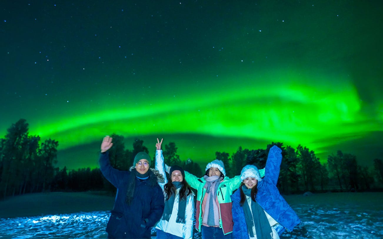 Guests in overalls viewing Northern Lights in Rovaniemi, Finland.