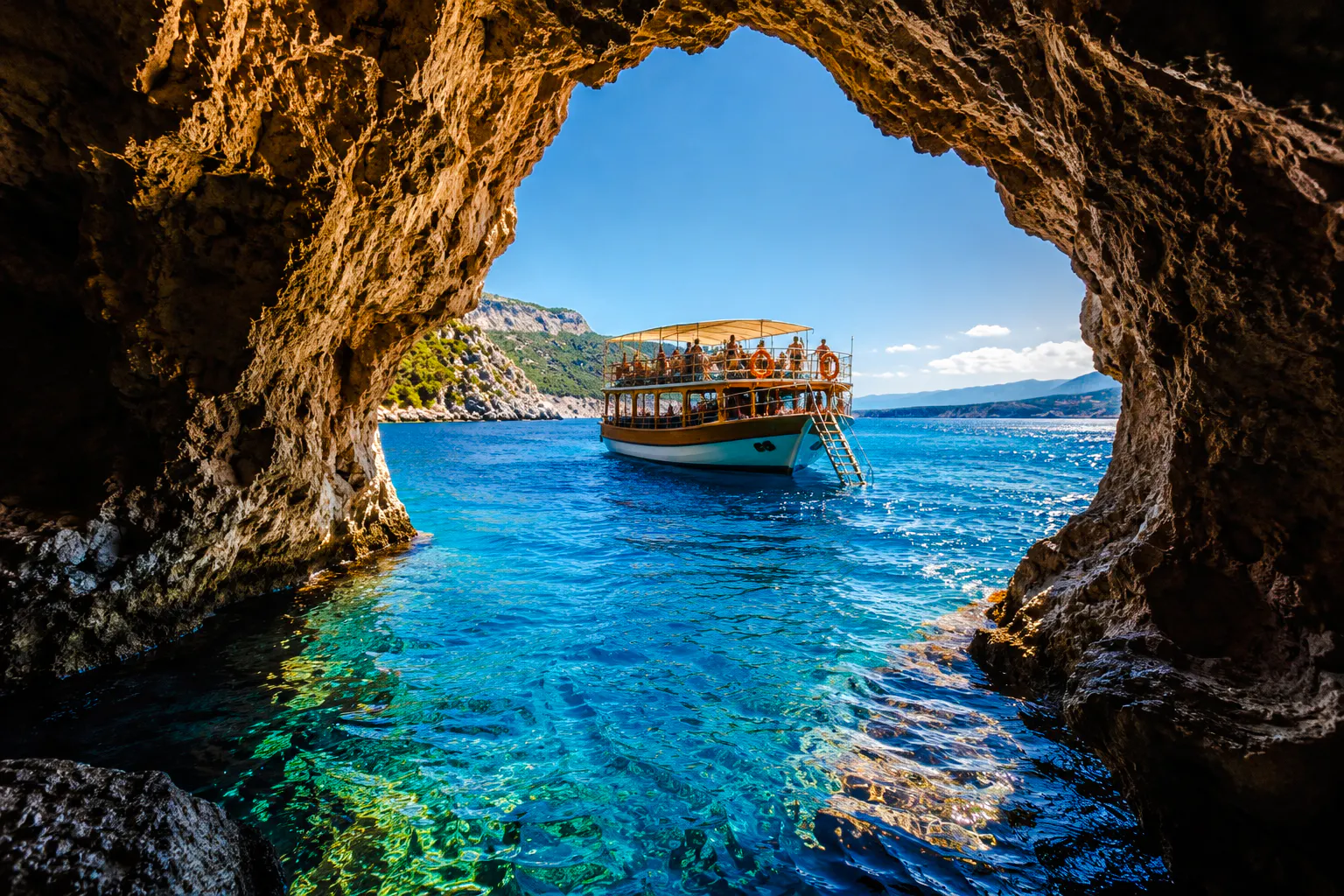 Cruise boat near rocky cave entrance on Alanya coast, Turkey.