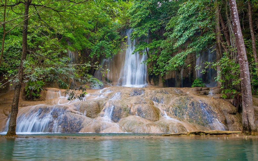 Sticky Waterfall cascading over limestone rocks surrounded by lush greenery in Chiang Mai.