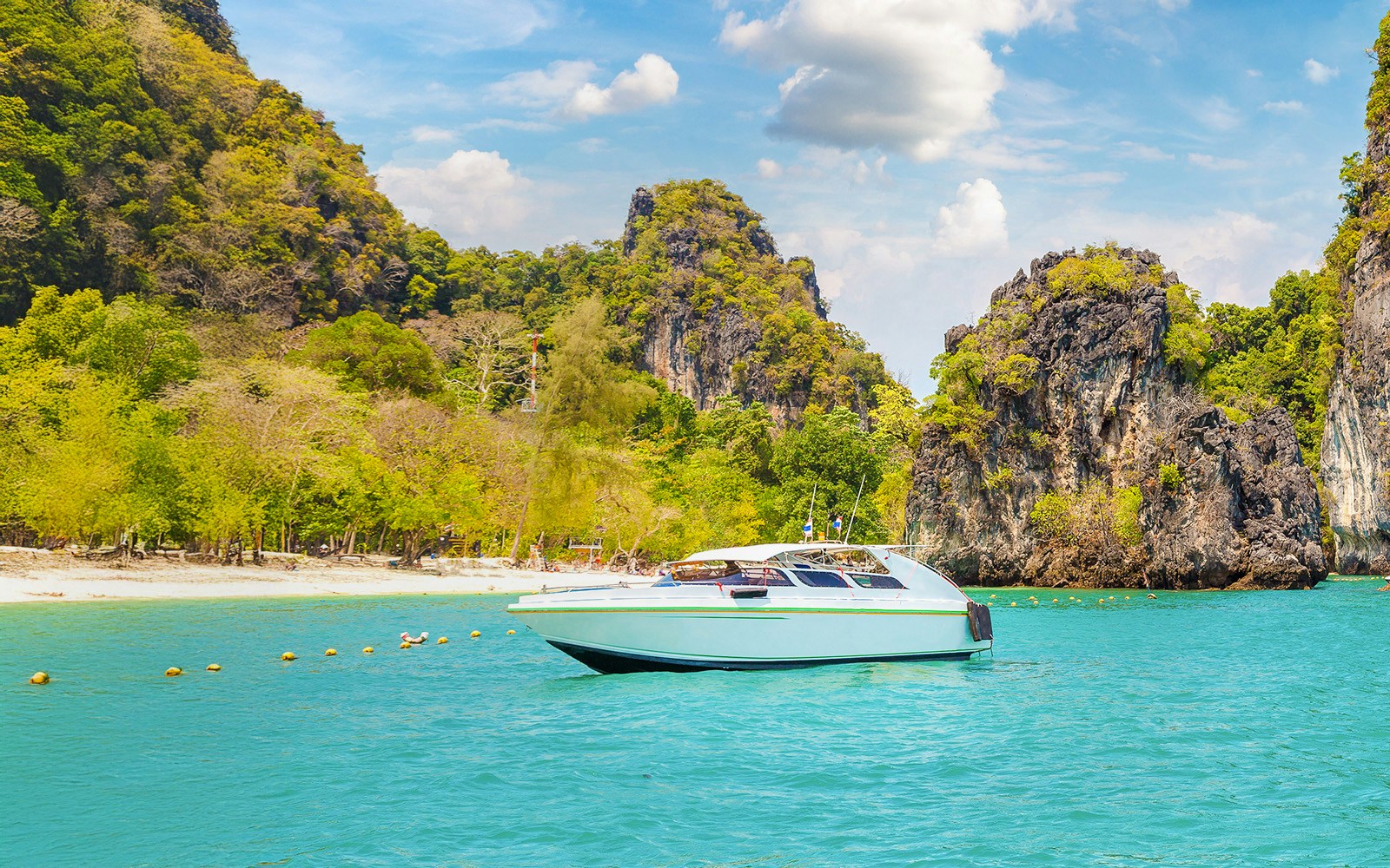 Speedboat on turquoise water near limestone cliffs, Hong Island, Thailand.