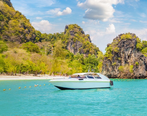 Speedboat on turquoise water near limestone cliffs, Hong Island, Thailand.
