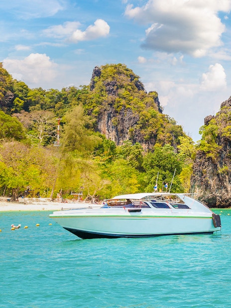 Speedboat on turquoise water near limestone cliffs, Hong Island, Thailand.