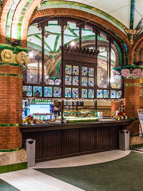 Palau de la Musica Catalana counter area with stained glass and brick arches.