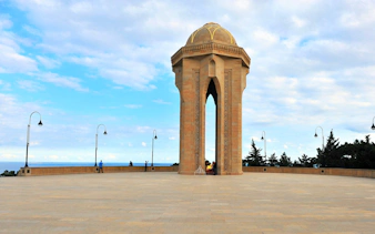 Eternal Flame memorial at Martyrs' Lane, Baku with surrounding plaza and sky.