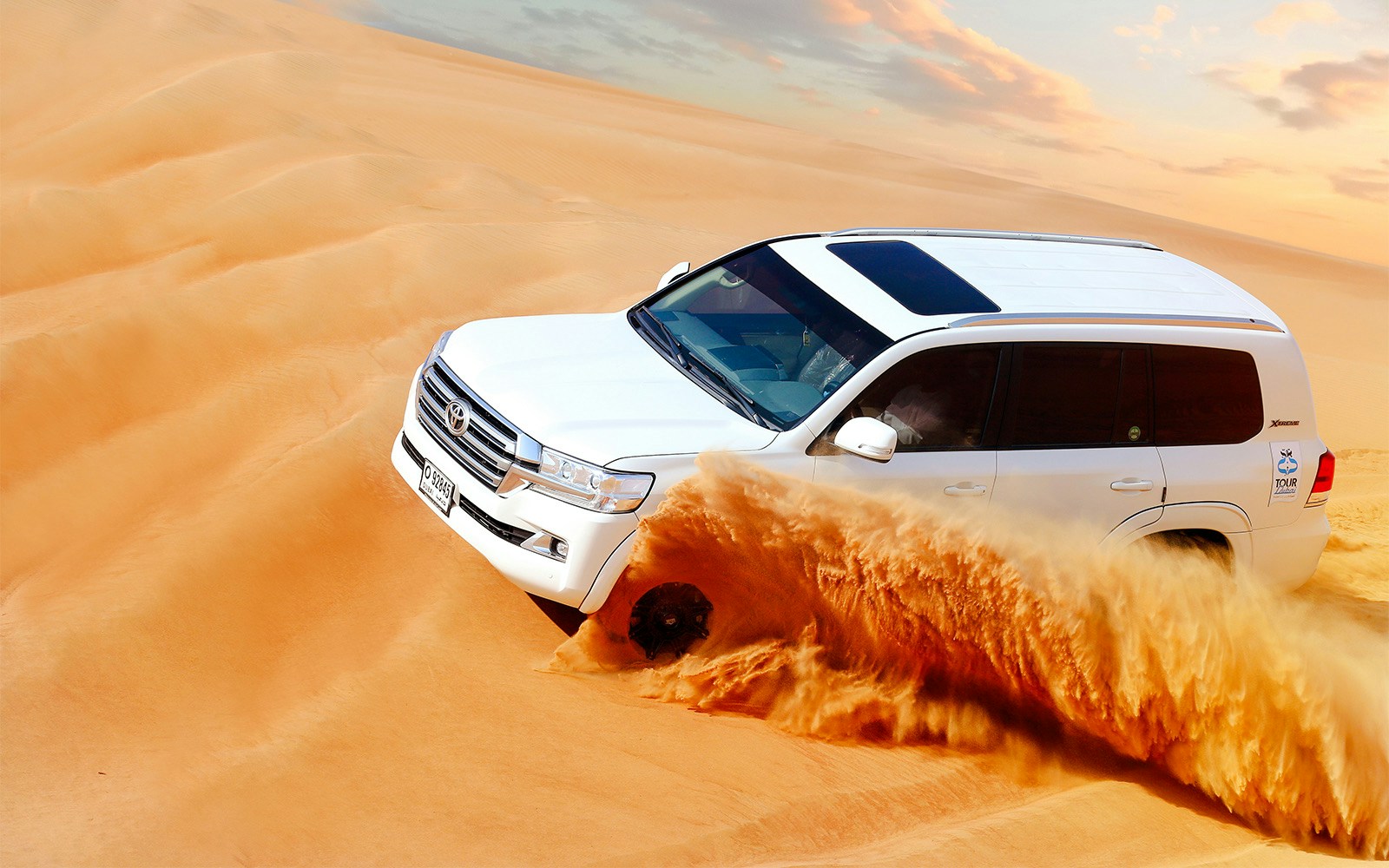 Dubai desert dune bashing with 4x4 vehicle on sandy dunes under clear blue sky.