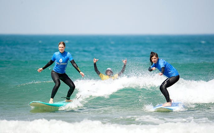 Surf lesson participants riding waves in Costa da Caparica.