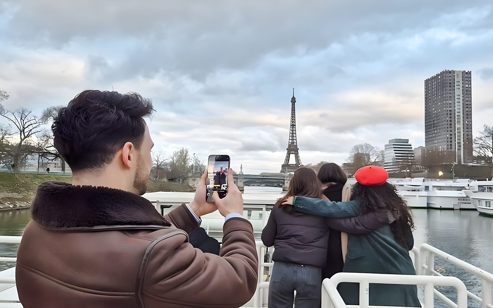 Tourists on Seine River cruise photographing Eiffel Tower, Paris.