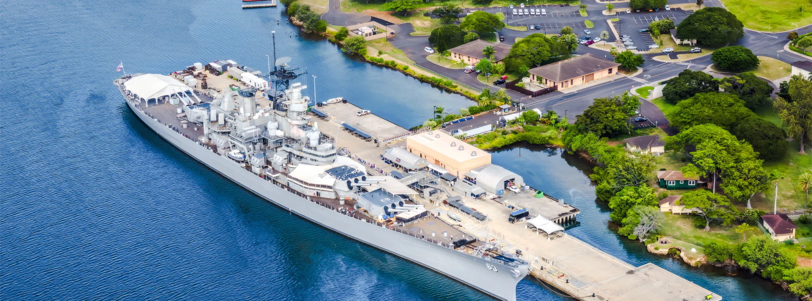 Battleship Missouri Memorial docked at Pearl Harbor, Hawaii, with surrounding landscape.