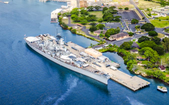 Battleship Missouri Memorial docked at Pearl Harbor, Hawaii, with surrounding landscape.