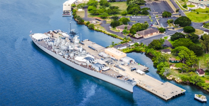 Battleship Missouri Memorial docked at Pearl Harbor, Hawaii, with surrounding landscape.