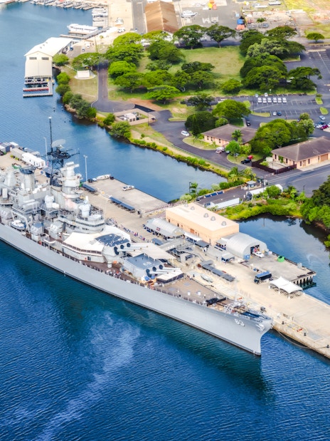 Battleship Missouri Memorial docked at Pearl Harbor, Hawaii, with surrounding landscape.