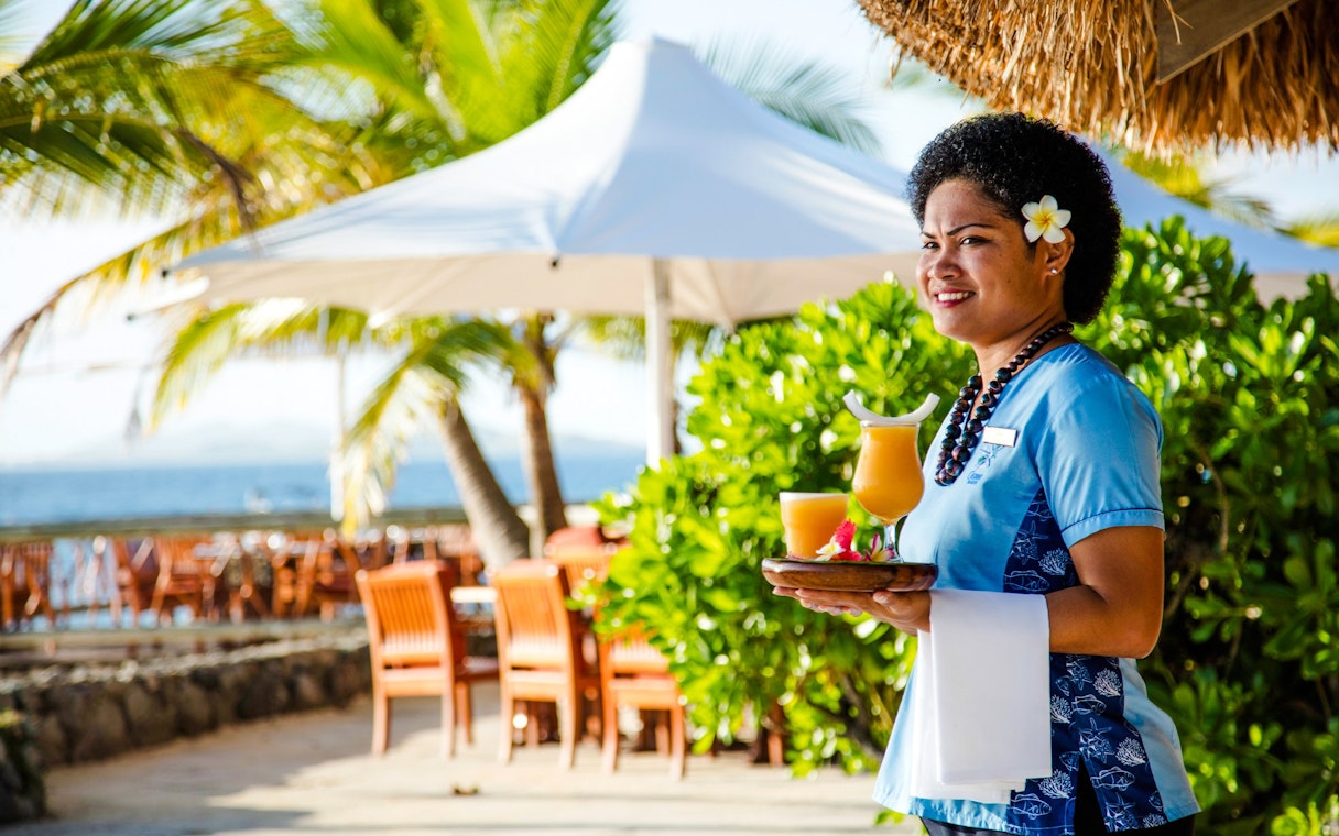 Staff member holding tropical drinks at Castaway Island, Fiji.