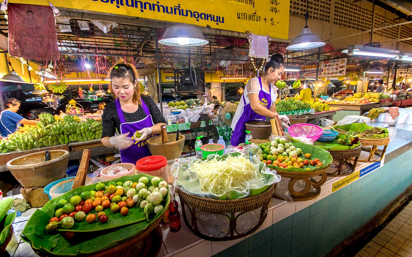 Chiang Mai market vendors preparing fresh produce during night bike tour.