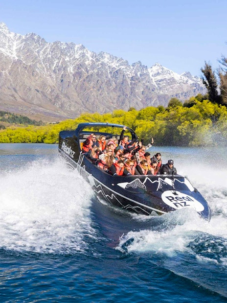 Jet boat navigating Kawarau River rapids with passengers in Queenstown, New Zealand.